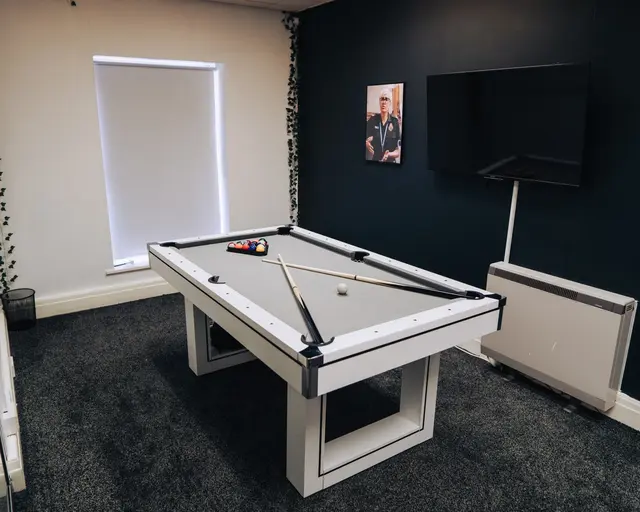Office boardroom transformed into a pool table setup for team recreation.
