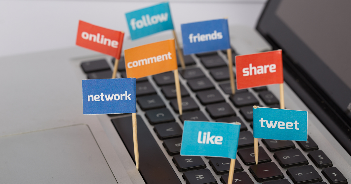 Colorful flags with social media words like like, share, follow, and tweet on laptop