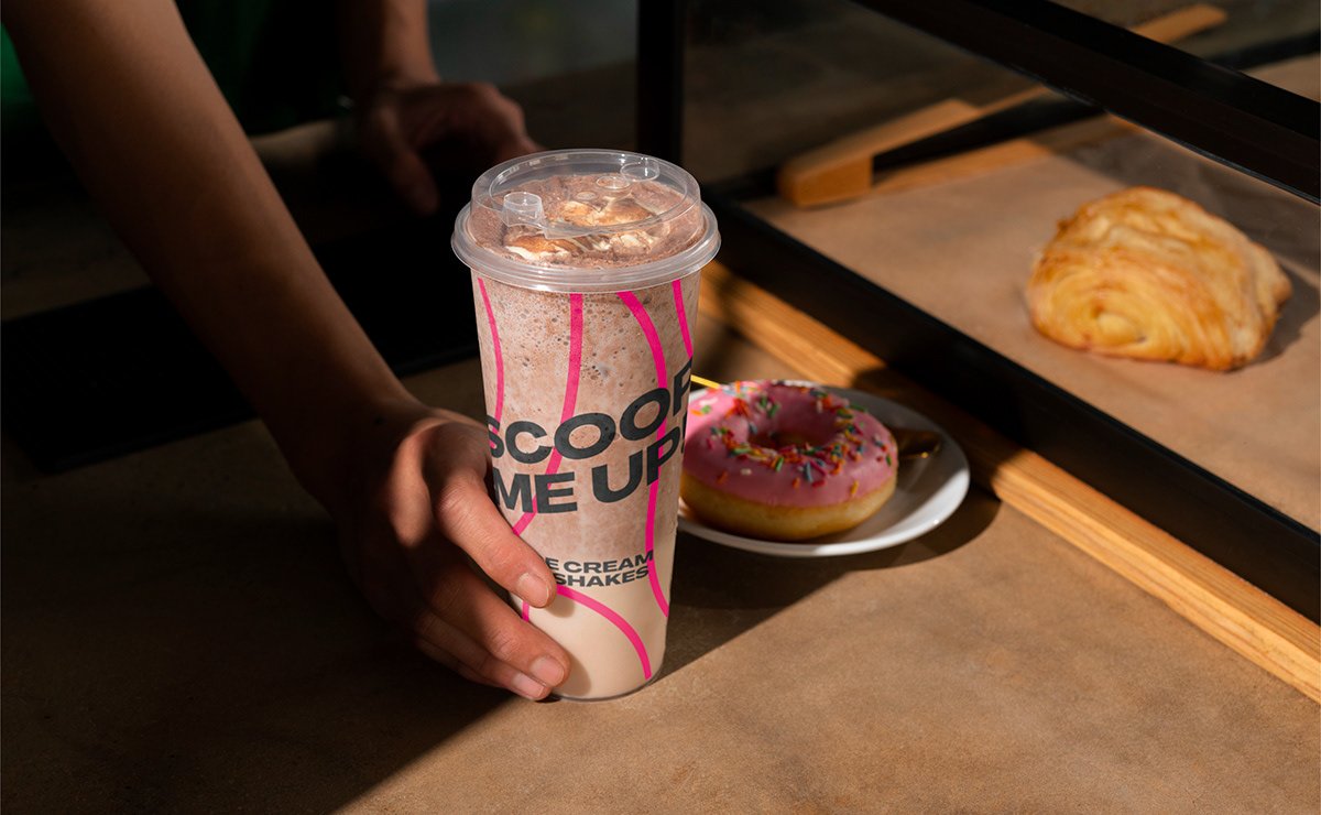 Barista preparing a dessert and beverage behind the Scoop café counter.