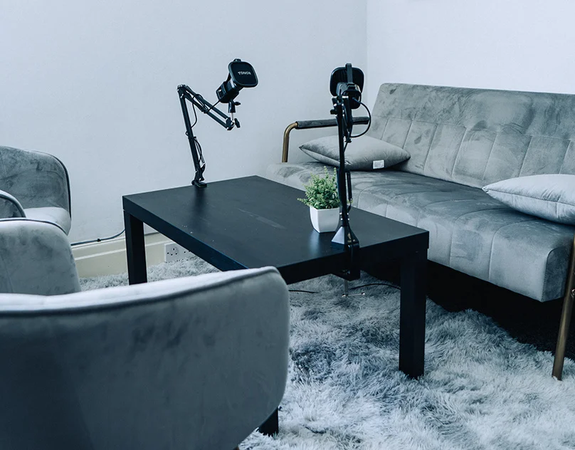Cozy podcast recording studio with microphones, table, and chairs.