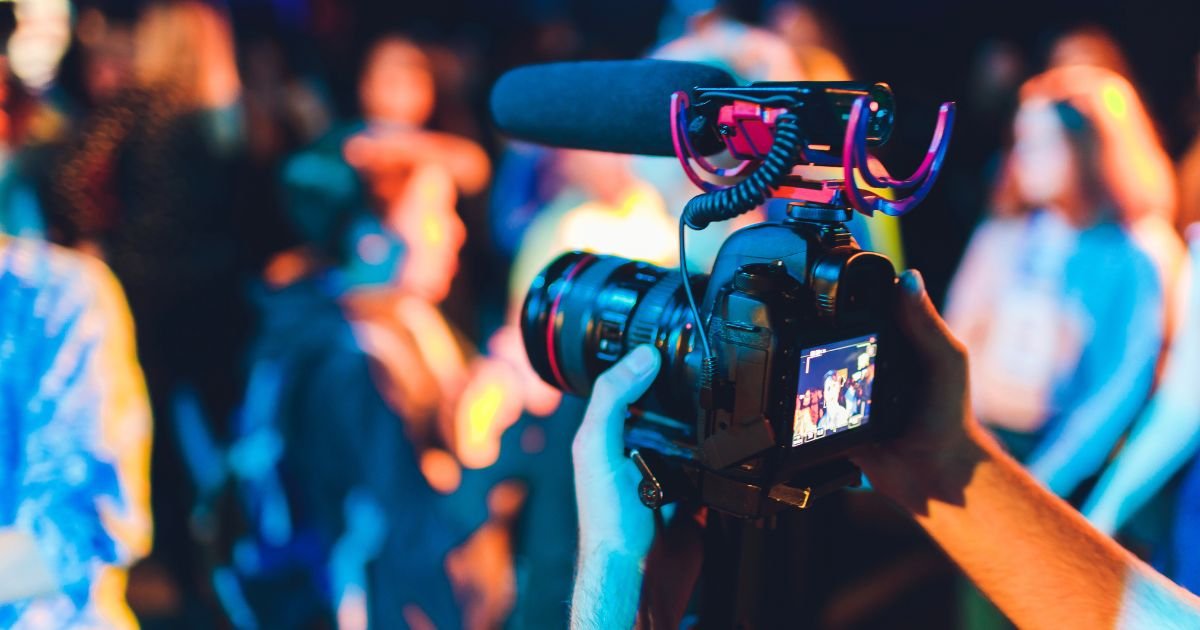Professional video camera recording a live event with audience in the background