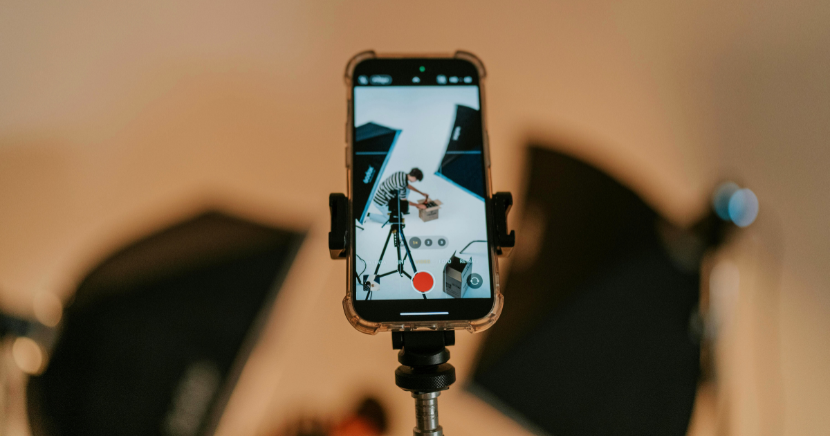Smartphone mounted on a tripod recording a video setup with studio lights in the background